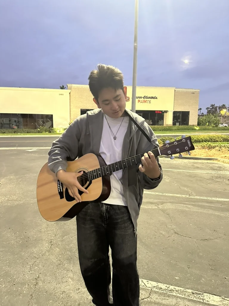 Aiden playing an acoustic guitar outdoors