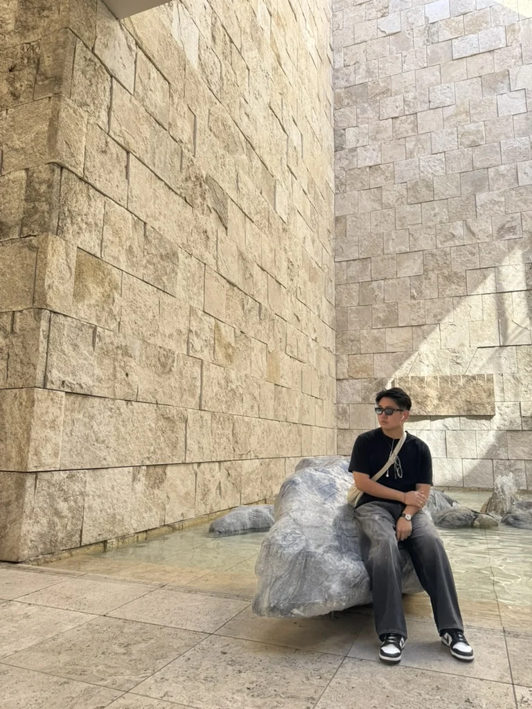 Aiden beside a historic stone wall