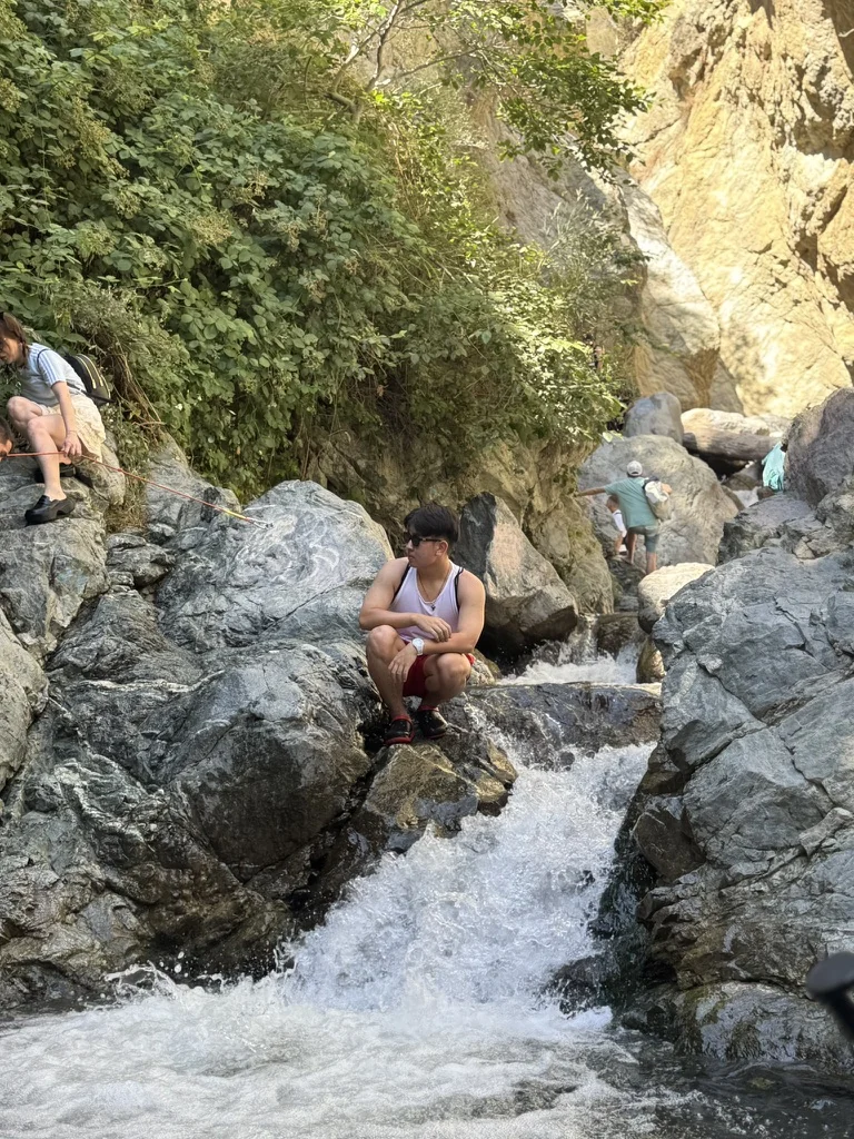 Aiden sitting beside a rocky waterfall
